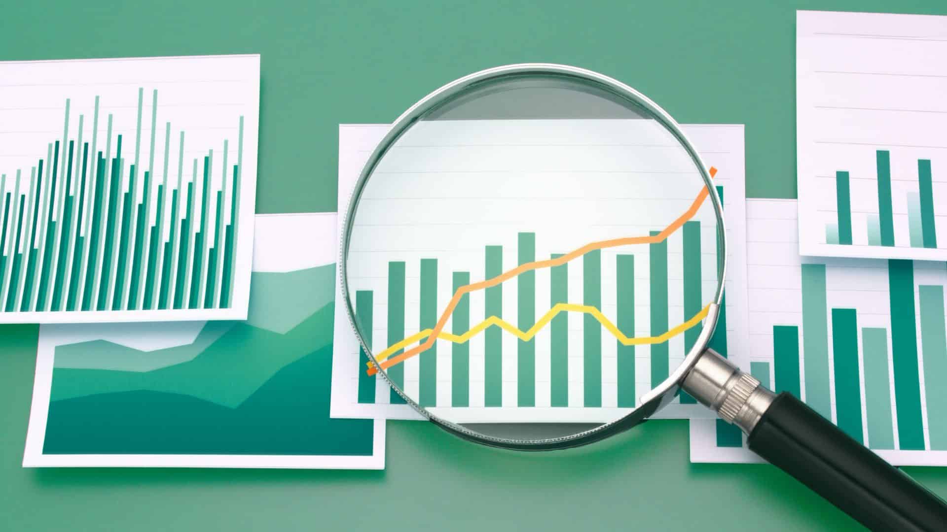 large magnifying glass above four illustrative charts