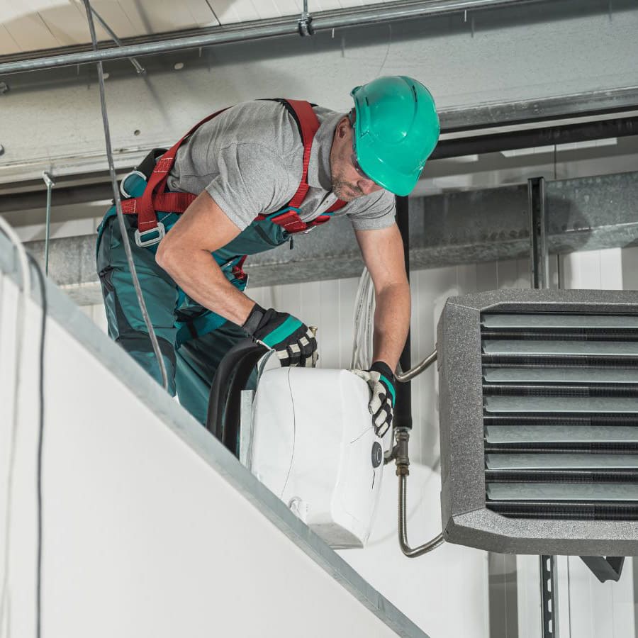 a HVAC technician servicing a piece of equipment; he is wearing a netgain-green hard hat