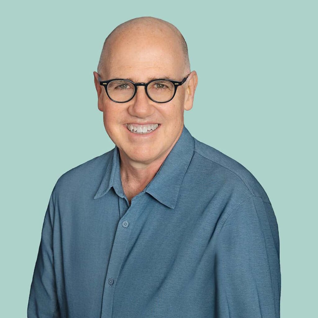 Biff Jennings, man wearing a blue polo shirt, smiling against a seafoam green background
