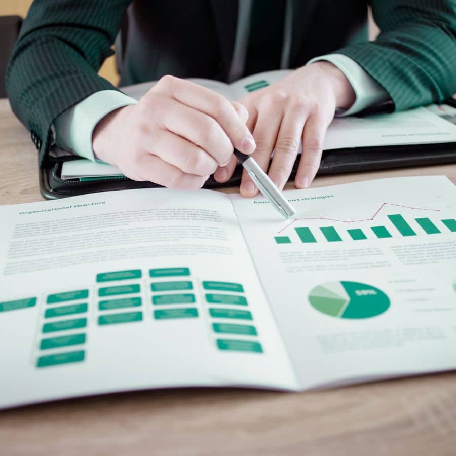 person using a pen to draw attention to a certain part of a financial report