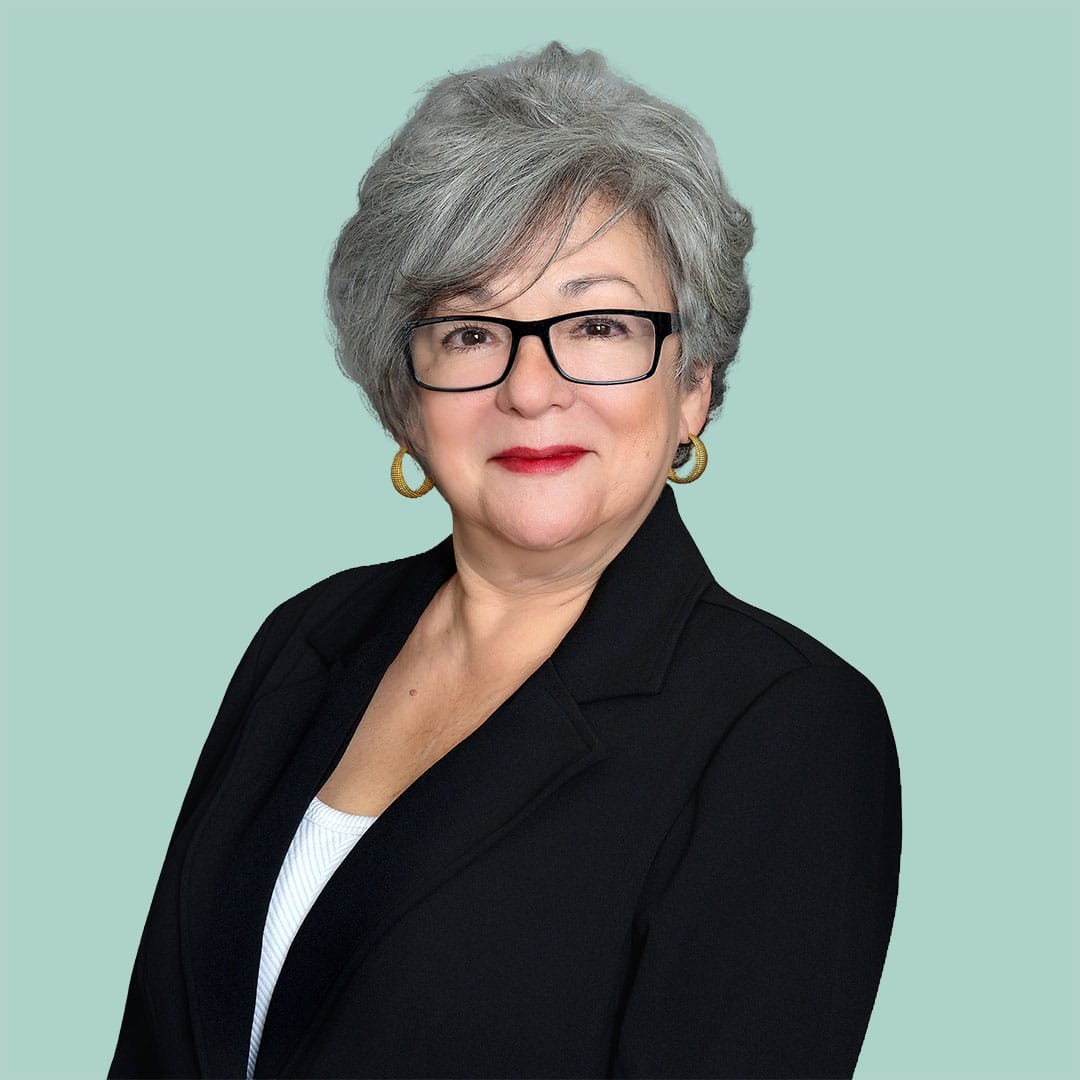 Alicia Saenz's headshot – woman wearing glasses and a blazer smiles at the camera